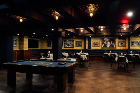 Dark-themed bar, lounge with pool table and framed pictures on the wall.