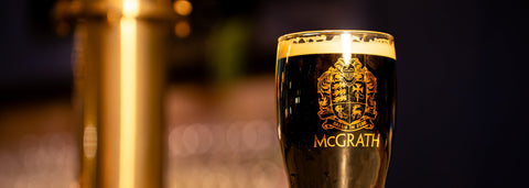 Freshly poured House of McGrath dark beer in branded pint glass