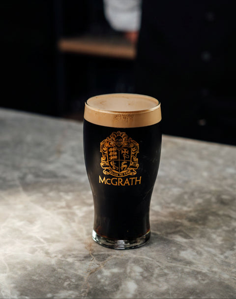 Pint glass featuring the McGrath logo on a marble surface.