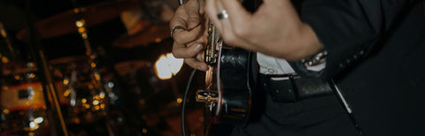 Close-up of a person's hands holding and playing an electric guitar on stage.
