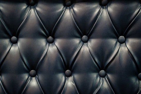 Close-up of a navy tufted leather surface with a diamond pattern and round button details.