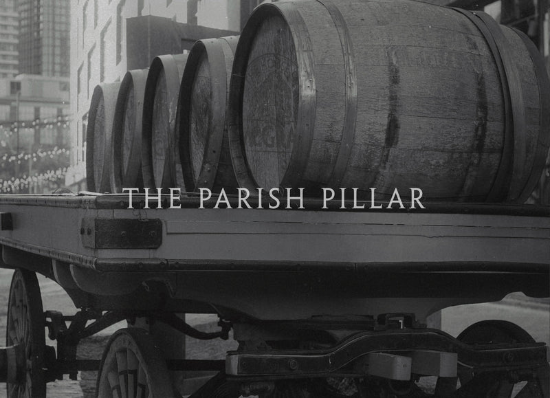 Black and white photograph showing a wagon loaded with large wooden barrels, with the text 'THE PARISH PILLAR'.